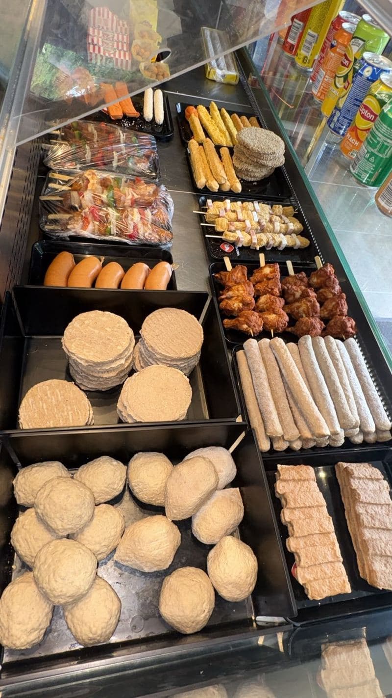 La vitrine réfrigérée de la friterie, garnie de fricadelles, brochettes, boulettes et cervelas